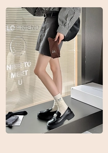 Detail of knit socks with sequined bows paired with black platform leather shoes
