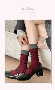 Detail of burgundy ribbed knit socks with grey trim styled with black Mary Jane shoes