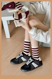Detail of red and cream striped socks with delicate white embroidered bows on the side