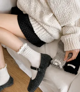 Detail of ruffled lace cuffs on stylish mid-calf cotton socks in creamy white and grey