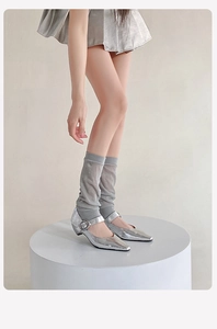 Detail of silver metallic pointed-toe Mary Jane shoes paired with sheer mesh leg warmers