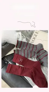 Detail of red and grey mid-tube socks with bow embroidery and high-quality knit texture