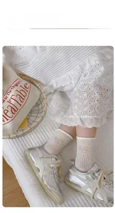 Detail showing white mesh mid-calf socks with floral embroidery and breathable net texture