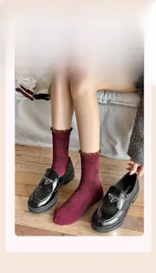 Detail of burgundy crew socks with bow pattern and brown ruffled trim in loafers