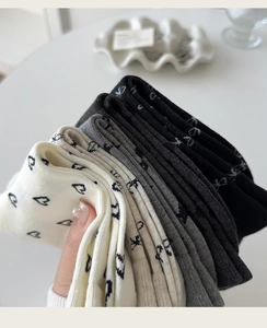 Detail of cotton crew socks featuring knitted heart and bow patterns in three colors