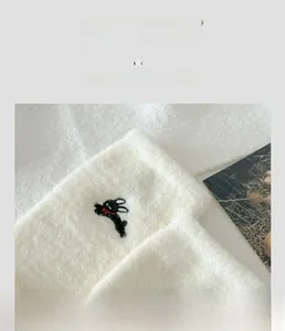 Close-up of plush white knit sock featuring a cute rabbit embroidery and elastic cuff