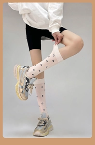 Detail of pink cotton mid-calf socks with black OBRNGO lettering and chunky sneakers