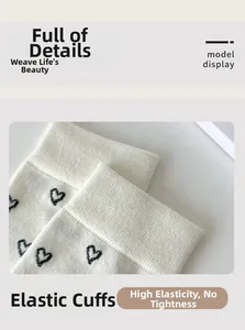 Detail of white cotton socks with black heart pattern showing elastic ribbed cuff texture