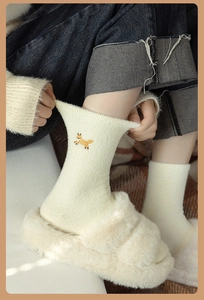 Detail of warm fluffy beige socks featuring a cute fox embroidery for winter home wear