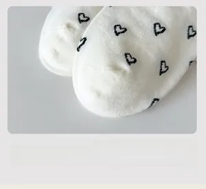 Detailed macro view of white cotton socks featuring black heart patterns and flat toe seams