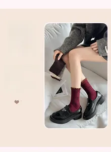 Detail of burgundy mid-tube socks featuring bow jacquard patterns and ruffled edges