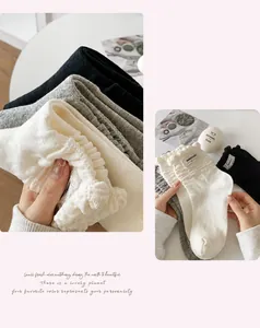 Detailed knit texture of ruffled mid-tube socks in black, grey, and white cotton blend