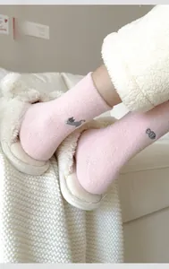Macro shot of pink winter socks featuring cute gray cat embroidery and thick fabric