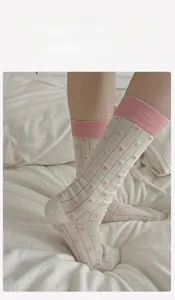 Detailed close-up of cream crew socks with pink heart patterns and vertical knit texture