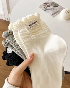 Close-up of knit cotton socks with ruffled cuffs and branded labels in soft lighting