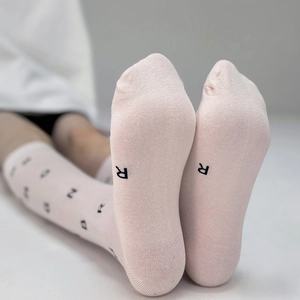 Pale pink knitted mid-calf socks featuring black alphabet patterns and cotton blend texture