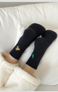 Detail of thick black plush thermal socks with cute giraffe embroidery on soft fabric