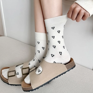 Women's cream cotton crew socks featuring black heart patterns and elastic ribbed cuffs