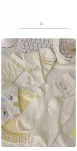 Close-up of cream crew socks featuring polka dots, smiley faces and breathable mesh texture