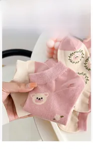 Detailed texture of pink knit cotton socks with cute cartoon bear and floral patterns