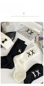 Close-up of ribbed cotton socks with delicate bows and pearl accents in black and white