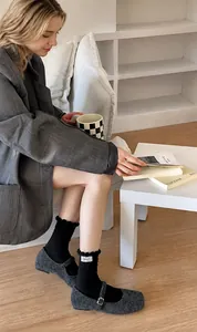 Detail showing black ruffled cuff socks paired with grey wool Mary Jane shoes