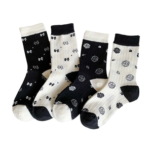 Four pairs of white and black crew socks featuring bowknot and rose floral patterns