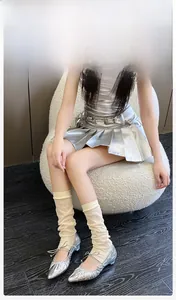 Detail of breathable cream leg warmers styled with silver metallic skirt and ballet shoes