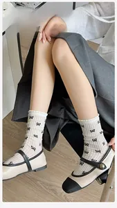 Detail of white cotton crew socks with black bow patterns worn with Mary Jane shoes