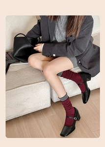 Detail of red and grey knitted socks worn with black square-toe Mary Jane shoes