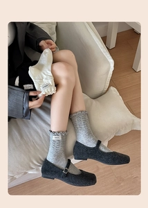 Close-up of knit mid-calf socks with ruffle trim and side label in home setting
