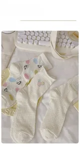 Detail of white mesh socks with colorful polka dots and cute smiley face embroidery