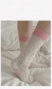 Detail of white cotton crew socks with pink hearts and breathable hollow-out texture