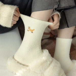 Fuzzy cream thermal crew socks with fox embroidery being stretched for elasticity