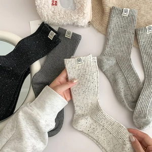 Women's ribbed speckled mid-tube socks in neutral tones with minimalist fabric label