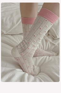 Detail of white cotton mid-calf socks featuring pink hearts and vertical ribbed texture