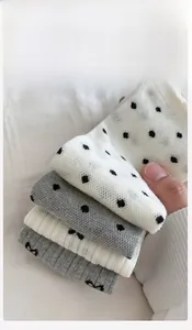 Close-up of ribbed knit cotton socks with black polka dots and wavy ruffled cuffs
