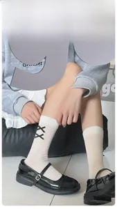 Close-up of white ribbed crew socks with black ribbon bow and reinforced heel design