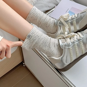 Fashionable grey flecked rib knit crew socks with fabric label shown with silver sneakers