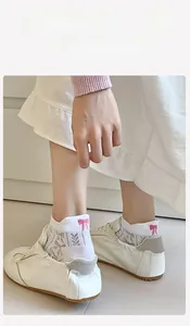 Detail of white cotton mesh socks with pink bow embroidery and heart cutout pattern
