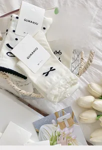 Detailansicht der weißen Baumwollsocken mit schwarzen Schleifen und Punktmuster-Struktur