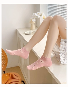 Pink low-cut cotton socks with cute bear pattern worn by a model in a minimalist setting