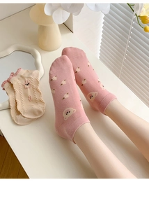 Detail of pink and cream cotton socks featuring cute cartoon bear patterns and wavy edges