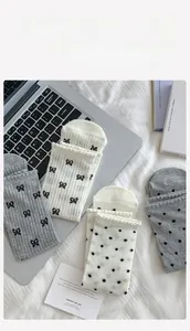 Detail of mesh crew socks with chic black bow patterns and polka dots in grey and white