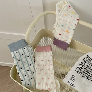 Three pairs of patterned cotton crew socks for women on a decorative metal shelf