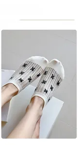 Detail of cream mesh knit socks featuring black bow prints and seamless toe finish