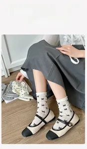 Detail of cream bow print socks with ruffled edges worn with Mary Jane shoes