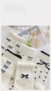 Detail von cremeweißen Baumwollsocken mit schwarzen Schleifen und Punkten