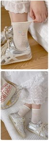 Detailed view of white mesh socks with delicate pink and yellow floral embroidery