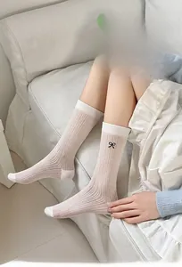 Detail of white slouch socks with vertical stripe texture and black bow embroidery